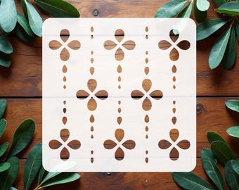 May include: A square white stencil featuring a repeating pattern of four-petaled flower shapes arranged in vertical columns, interspersed with small teardrop-shaped cutouts that create a delicate, symmetrical design across the entire surface.