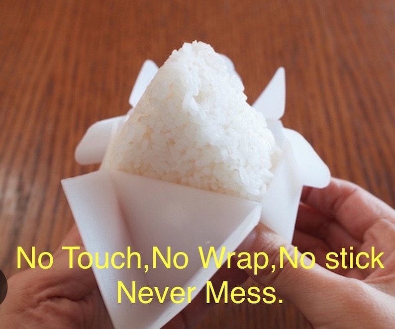 May include: White rice is being pressed into a white plastic mold. The mold is shaped like a triangle and has a flap that folds over the rice. The text "No Touch, No Wrap, No Stick Never Mess." is visible in the image.