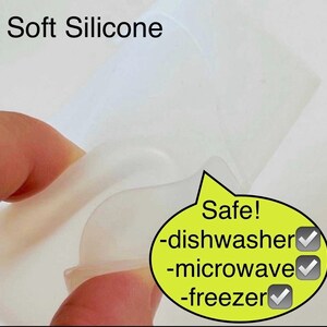 May include: A close-up of a clear silicone mold, showing its flexibility. The mold is labeled "Safe!" with checkmarks next to "dishwasher", "microwave", and "freezer".