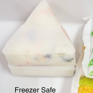 May include: A white, triangular, freezer-safe container with a layer of colorful food inside. The container is labeled "Freezer Safe".