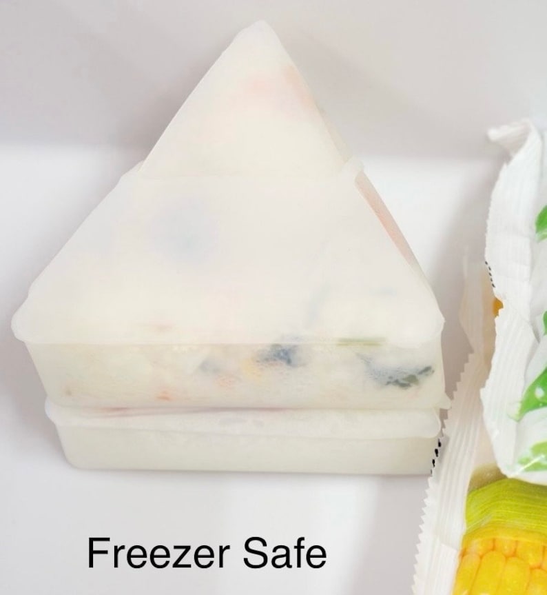 May include: A white, triangular, freezer-safe container with a layer of colorful food inside. The container is labeled "Freezer Safe".