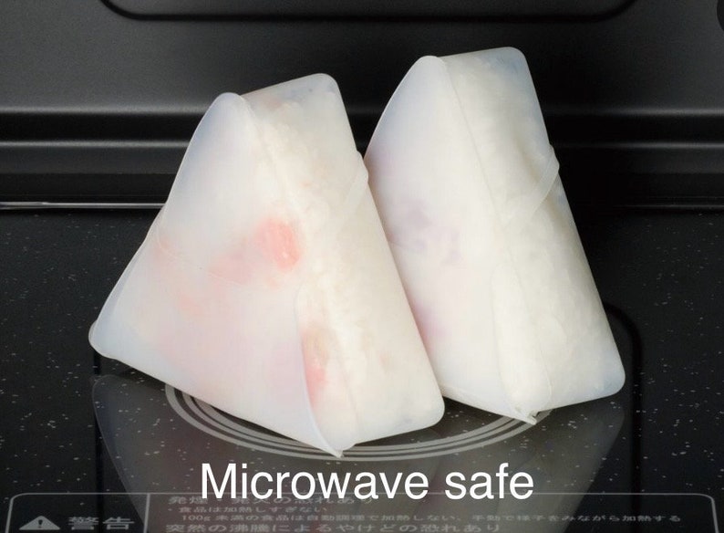 May include: Two white silicone food covers shaped like triangles. The covers are on a black surface and the text "Microwave safe" is printed below them.