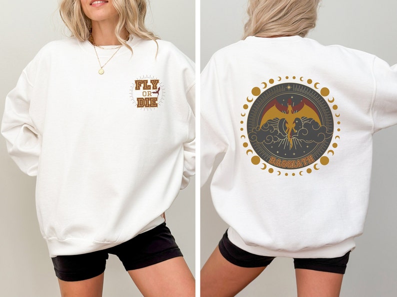 May include: White sweatshirt with a front graphic that reads "FLY OR DIE" in a brown and gold design. The back features a circular design with a phoenix, clouds, and the word "BASUATH".