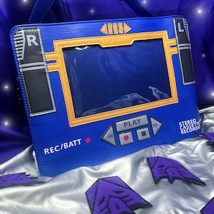 May include: Blue faux leather cassette recorder bag with a clear plastic window, a red record button, and the text "REC/BATT" and "STEREO CASSETTE RECORDER".