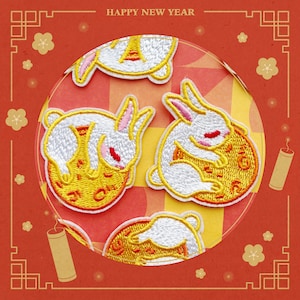 May include: Four embroidered patches featuring white rabbits holding yellow mooncakes. The patches are on a red background with a white circle and the text "HAPPY NEW YEAR".