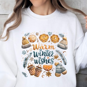 May include: White sweatshirt with a winter-themed design featuring oranges, hats, and the text "Warm winter wishes".