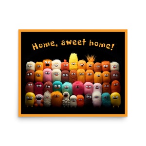 May include: A framed print featuring a collection of colorful, fuzzy monster characters with various expressions. The phrase "Home, sweet home!" is written across the top in a playful font, set against a black background.