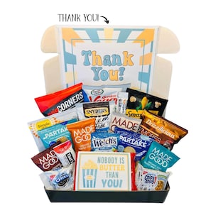 May include: A gift box filled with various snacks, including chips, cookies, and popcorn. The box features a colorful design with the words "Thank You!" and "Nobody is Butter Than You!" on a sign. A variety of snack brands are visible.