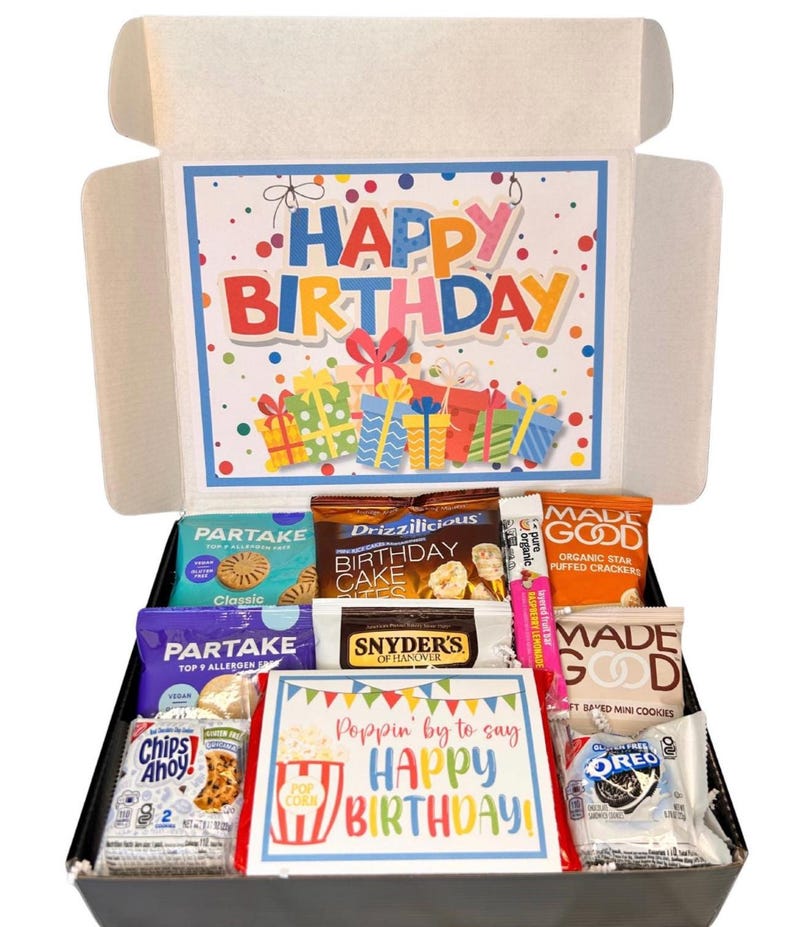 May include: A birthday gift box filled with snacks and treats. The box features a colorful "Happy Birthday" message and includes various packaged cookies, crackers, and candies. The overall theme is festive and celebratory.