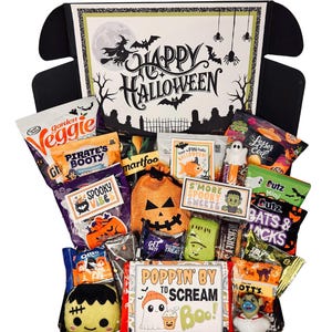 May include: A black gift box filled with Halloween-themed snacks and treats. The box lid features the text #1 FULL WITCH and HAPPY HALLOWEEN with witch and spider graphics. Contents include various branded snack bags, a pumpkin pouch, and a ghost toy.