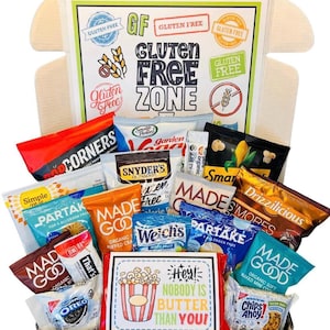 May include: A gluten-free snack box with various packaged snacks. The box is labeled 'Gluten Free Zone' and contains items like popcorn, crackers, cookies, and fruit snacks. The snacks are in a black tray with a card that says 'Hey! Nobody is butter than you!'