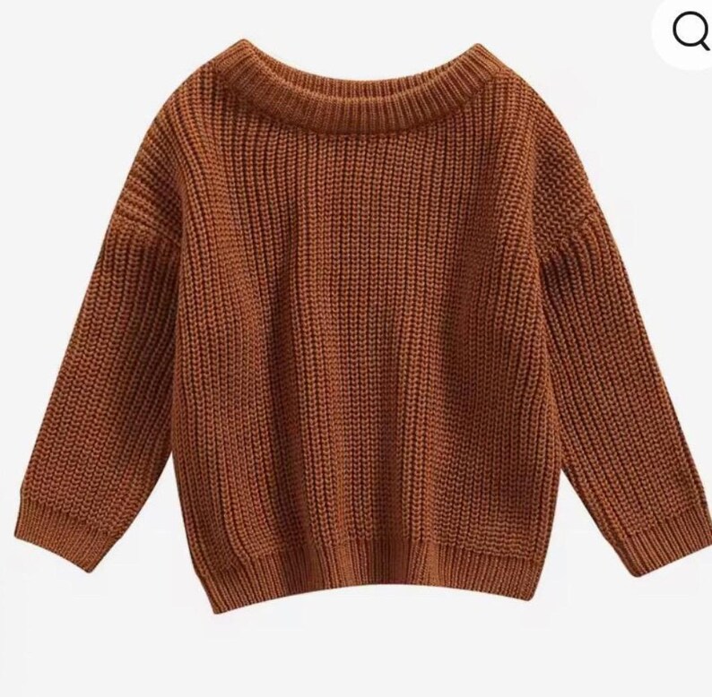 May include: A rust-colored, ribbed-knit sweater with a wide neckline and long sleeves. The sweater has a relaxed fit and a classic, comfortable style. The knitwear is a solid color, making it versatile for various outfits.