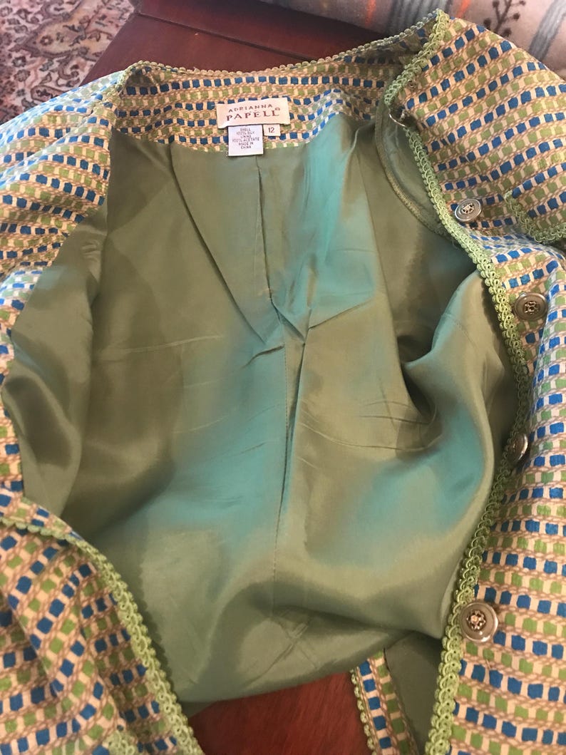 May include: A green and blue patterned jacket with a green lining. The jacket has a label that reads "Adrianna Papell" and "12".