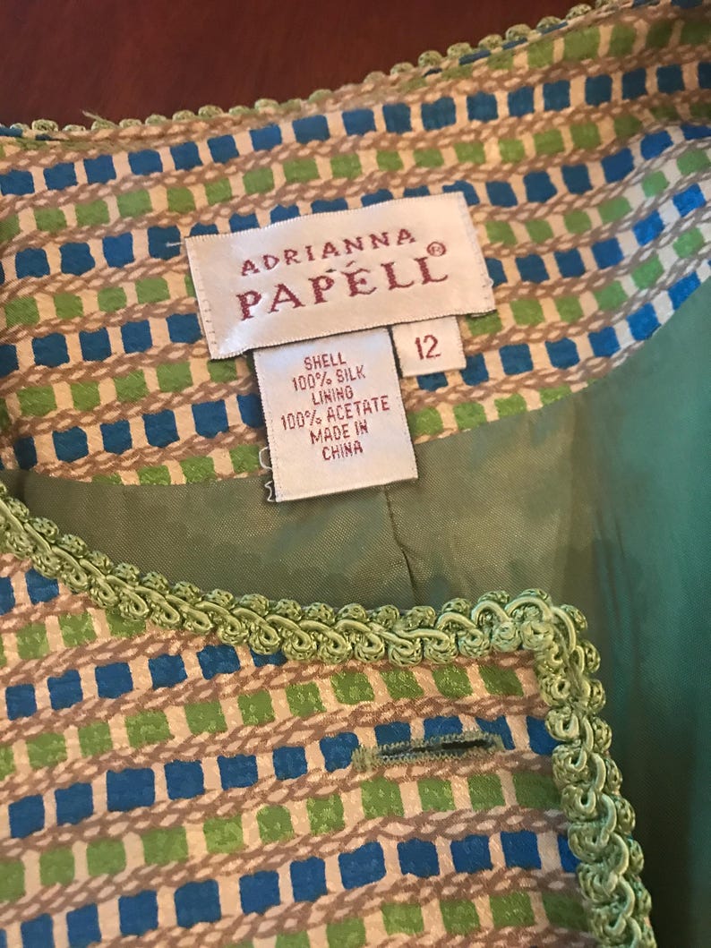 May include: A green and blue patterned jacket with a green trim. The label reads "Adrianna Papell" and "Shell 100% Silk Lining 100% Acetate Made in China" and "12".