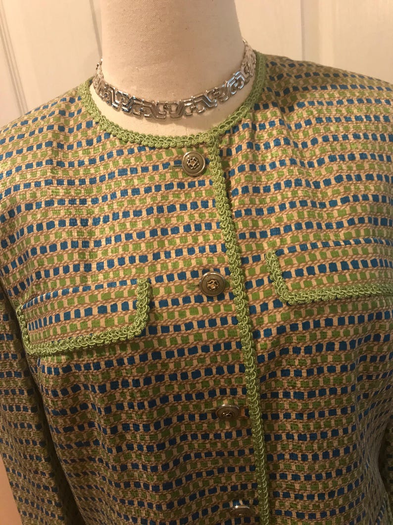 May include: A green and blue patterned blazer with a green trim and gold buttons.