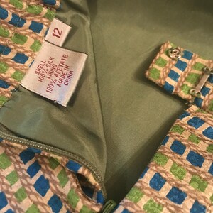 May include: A green, blue, and brown patterned dress with a zipper closure. The dress has a tag that reads "Shell 100% Silk Lining 100% Acetate Made in China" and a size tag that reads "12".
