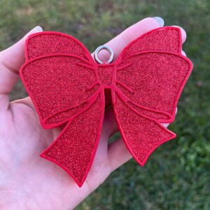 May include: A red glitter bow ornament with a silver loop for hanging.