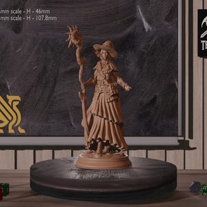 May include: A brown painted miniature figurine of a female wizard wearing a pointed hat and holding a staff. The figurine is standing on a round base. The text "32mm scale - H-46mm" and "75mm scale - H-107.8mm" is visible in the background.