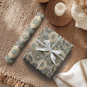 May include: A gift wrapped in blue and gold patterned paper with a white ribbon. The paper features a geometric design with stars and crescent moons.