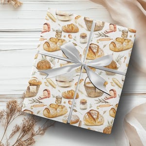 May include: White gift wrap with a watercolor design of various breads, pastries, and baking supplies. The design includes a white ribbon tied in a bow.