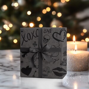 May include: Black and white gift wrap with a skull, hearts, and other graphic designs. The wrapping paper is tied with a black ribbon.
