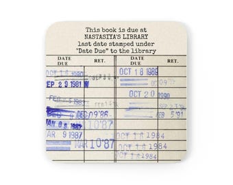 Puede incluir: Un posavasos cuadrado con un diseño de tarjeta de biblioteca vintage. La tarjeta tiene una cuadrícula de fechas y sellos, con el texto "This book is due at Nastasiya's Library". El posavasos es blanquecino.
