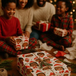 May include: A white gift box wrapped in festive paper with a pattern of cartoon faces wearing Santa hats. The box is tied with twine and decorated with a sprig of evergreen.