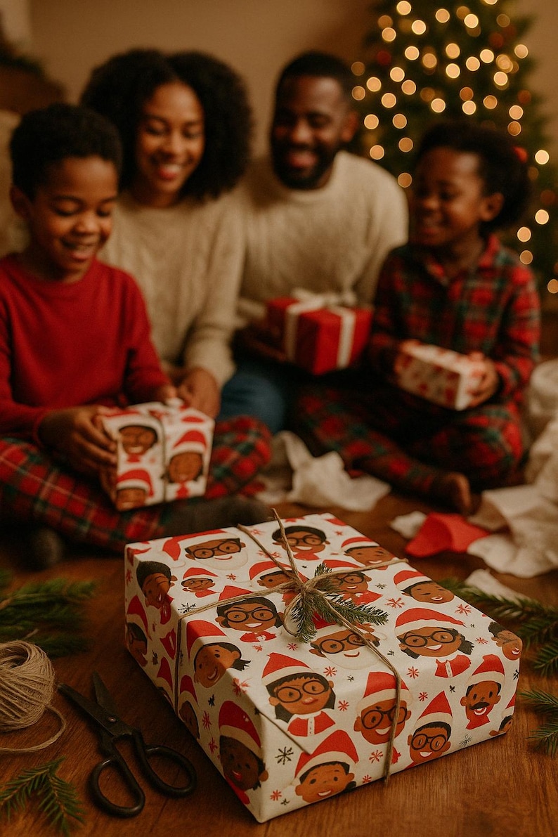 May include: A white gift box wrapped in festive paper with a pattern of cartoon faces wearing Santa hats. The box is tied with twine and decorated with a sprig of evergreen.