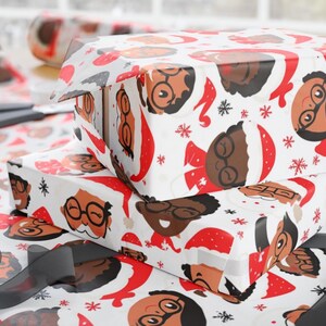 May include: White wrapping paper with a repeating pattern of cartoon faces wearing Santa hats. The faces are brown and have glasses. The background is white with red snowflakes.