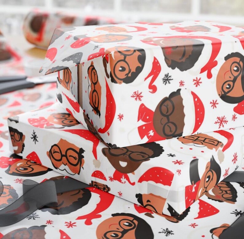May include: White wrapping paper with a repeating pattern of cartoon faces wearing Santa hats. The faces are brown and have glasses. The background is white with red snowflakes.