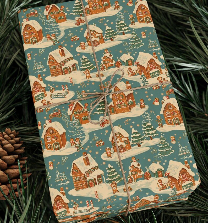 K&ouml;nnte beinhalten: Ein verpacktes Geschenk mit t&uuml;rkisblauem Hintergrund und einem sich wiederholenden Muster aus Lebkuchenh&auml;usern, schneebedeckten B&auml;umen und Figuren. Das Geschenk ist mit einer braunen Schnur-Schleife gebunden und von gr&uuml;nen Tannennadeln und einem Tannenzapfen umgeben.