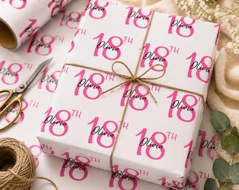 May include: White wrapping paper featuring a repeating pattern of the bright pink text 18th and the black cursive name Olivia. The paper is tied with brown twine, and a roll of the same paper and metal scissors are visible nearby.