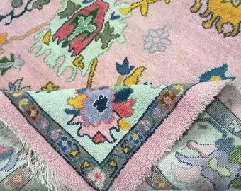 Könnte beinhalten: Ein rosa und grüner Teppich mit einem Blumenmuster. Der Teppich hat einen Fransenrand und ist aus Wolle.