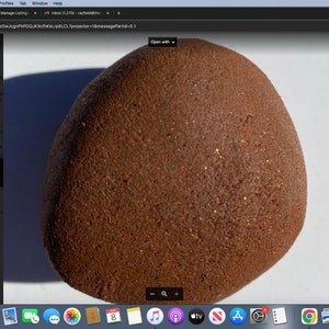 May include: A close-up of a large, round, brown rock with a rough, textured surface. The rock has a speckled appearance with small, shiny particles.
