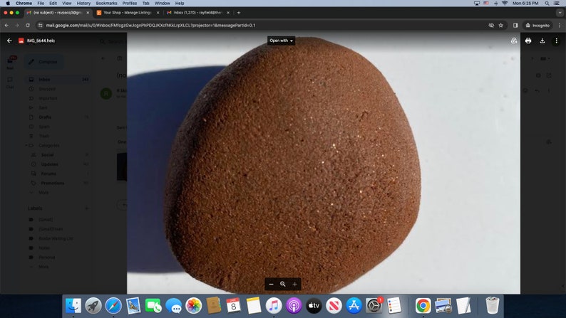 May include: A close-up of a large, round, brown rock with a rough, textured surface. The rock has a speckled appearance with small, shiny particles.