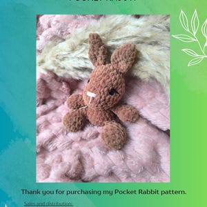 K&ouml;nnte beinhalten: Ein braunes geh&auml;keltes Taschenkaninchen auf einem rosa-wei&szlig;en flauschigen Untergrund. Das Bild enth&auml;lt den Text "Briar's Crochet Crafts Pocket Rabbit" und "Vielen Dank f&uuml;r den Kauf meines Taschenkaninchen-Musters."