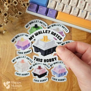 May include: A collection of stickers featuring mechanical keyboard switch designs. Each sticker has a different color scheme and the text "MY WALLET HATES THIS HOBBY". A colorful keyboard is in the background.