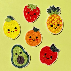 Op de afbeelding: Geborduurde fruitpatches met een gele citroen, rode aardbei, gele ananas, sinaasappel, groene avocado en rode appel. Elke patch heeft een lachend gezicht en is wit omlijnd.