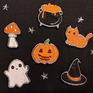 Pode incluir: Um conjunto de patches de ferro com tema de Halloween, incluindo um fantasma, uma abóbora, um chapéu de bruxa, um cogumelo, um caldeirão e um gato. Os patches são todos bordados com detalhes coloridos.
