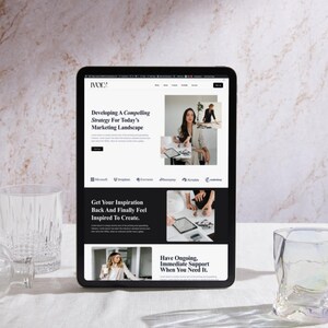 May include: A black tablet displays a website with the text "Developing A Compelling Strategy For Today's Marketing Landscape." The website features images of people working. Two clear glass tumblers are on the table.