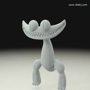 Puede incluir: Una criatura estilizada de color gris claro con una amplia sonrisa dentada y ojos grandes y redondos. La criatura tiene un cuello largo, dos piernas y dos pies. La imagen está sobre un fondo oscuro.