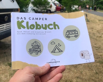 May include: A white book with the title "Das Camper Klobuch" and the text "Spaß, Rätsel und kreatives Wissen aus dem Camping Universum". The book has illustrations of a camper van, a tent, and a roll of toilet paper with a face.