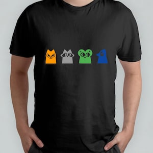 May include: A black t-shirt featuring a row of four cartoon animal faces. The animals are a cat, a raccoon, a frog, and a bird. The cat is orange, the raccoon is grey, the frog is green, and the bird is blue.