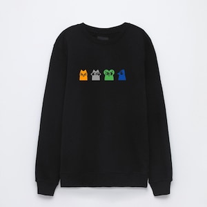 May include: Black long-sleeved sweatshirt with a graphic of four cartoon animals: an orange cat, a gray raccoon, a green frog, and a blue bird.