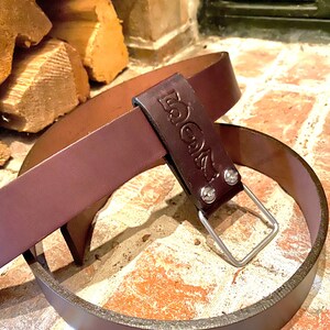 May include: A brown leather belt with a silver buckle and the word "BOOTS" embossed on the strap.
