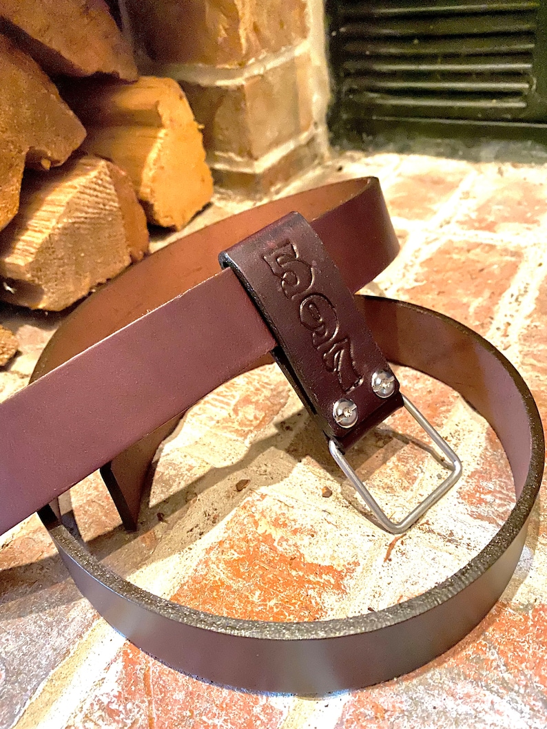 May include: A brown leather belt with a silver buckle and the word "BOOTS" embossed on the strap.