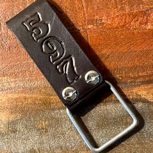 May include: A brown leather key chain with a metal ring and the number "5927" embossed on it.