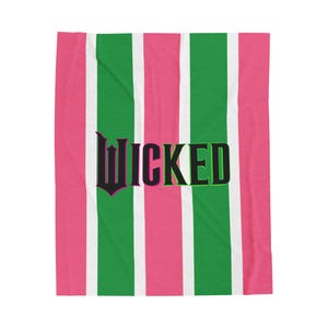 Può includere: Una coperta a righe rosa e verde con la parola "WICKED" in lettere nere.