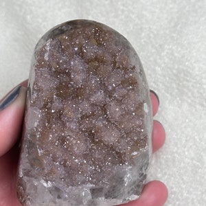 May include: A large, clear quartz crystal with a brown druzy interior. The crystal is shaped like a heart and has a smooth, polished surface.