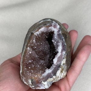 May include: A large amethyst geode with a natural, rough exterior and a hollow interior lined with sparkling purple crystals.